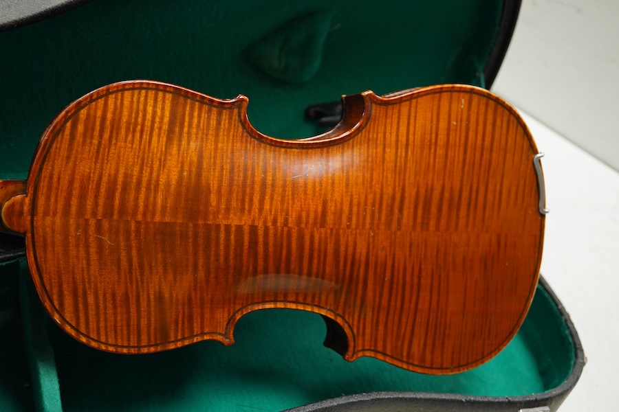 Four cased violins; an early 20th century violin, body 36cm, fitted with a microphone pick up taking a quarter inch jack plug, an early 20th century half size violin, body 32cm, and two student violins. Condition - poor